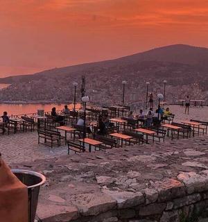 日落时分，一群人坐在海滩的桌子旁