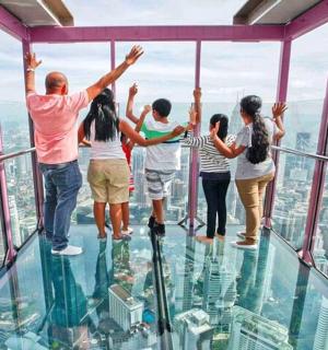a group of people standing on the glass floor of a skyscraper