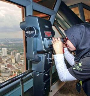a woman looking through a camera in an observation tower