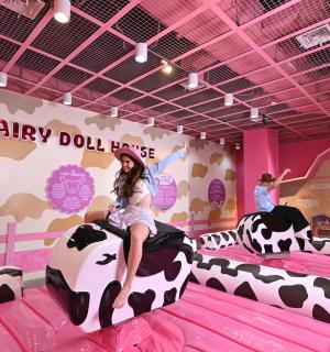 一名女子骑着一头假牛在假牛房里