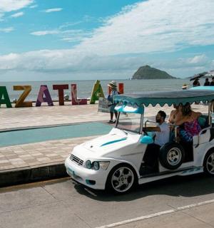 a group of people riding a golf cart near the beach