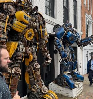 muž stojící před obří robotickou sochou