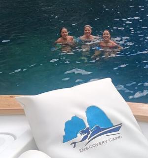three women swimming in the water on a boat