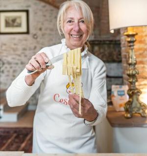 一位老妇人举着一盘意大利面