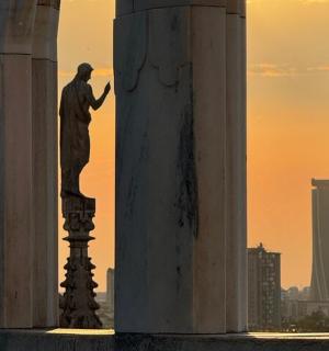 posąg mężczyzny stojącego na słupie między dwiema kolumnami