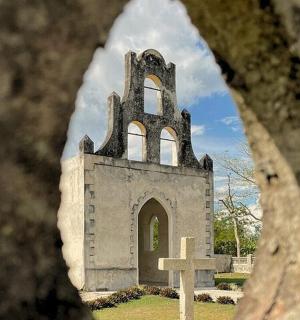 uma igreja com uma torre e uma cruz em um cemitério