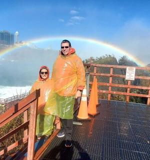 two people standing on a bridge with a rainbow in the background