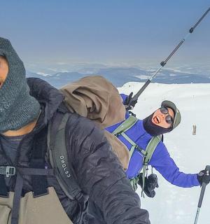 dva lidé stojící na vrcholu zasněženého svahu