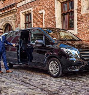 一名西装革履的男子站在一辆黑色货车旁