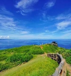 a path on a hill with the ocean in the background
