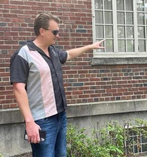 a man pointing at a window on a brick building
