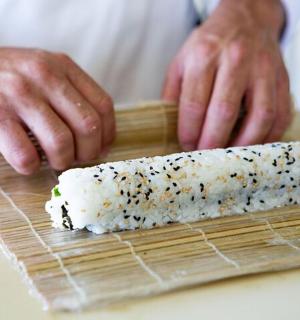a person is preparing sushi on a cutting board