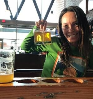 一位女士坐在桌边，手里拿着一杯啤酒