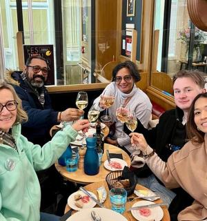 skupina lidí sedících u stolu a pijících víno