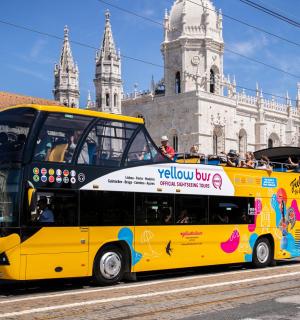 a yellow double decker bus driving past a building