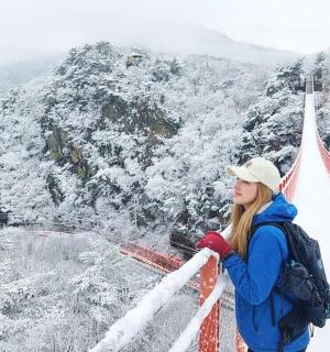a woman standing on a suspension bridge in the snow