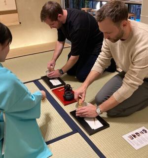 three people sitting on the floor looking at a table