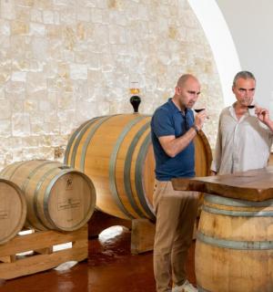 two men standing in front of barrels in a room