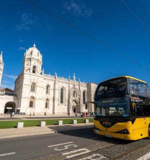a yellow double decker bus driving past a building