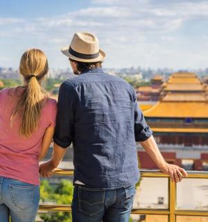a man and woman standing on a balcony looking at a city