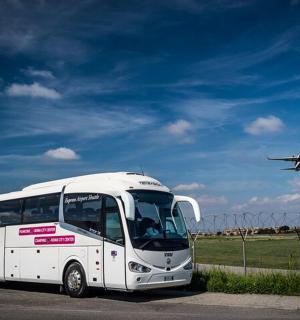 bílý autobus zaparkovaný na parkovišti s letadlem