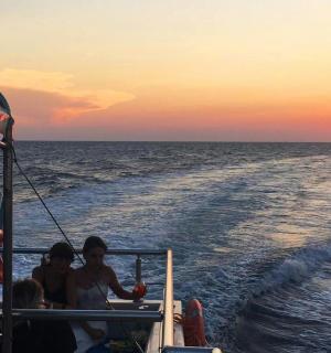 eine Gruppe von Menschen, die bei Sonnenuntergang auf einem Boot fahren