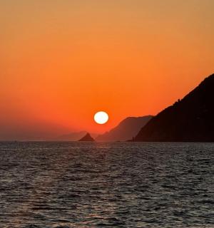 Západ slunce nad vodou s horami v pozadí