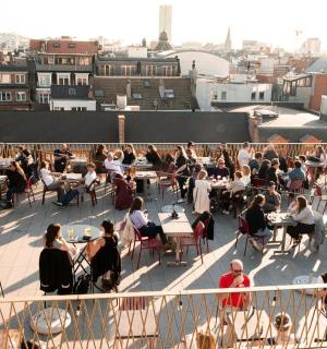 un grup de persones assegudes a taules en una teulada