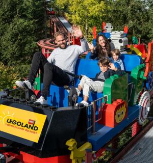 a man and woman riding on a toy train