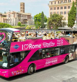 růžový dvoupatrový autobus jedoucí po ulici