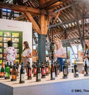 eine Gruppe von Frauen steht um eine Ausstellung von Weinflaschen herum