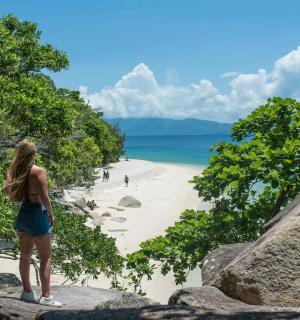 žena stojící na skále a dívající se na pláž