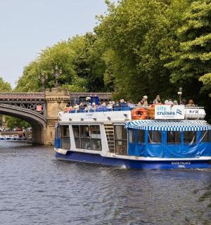 ein blau-weißes Boot auf einem Fluss in der Nähe einer Brücke
