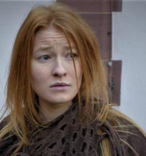 женщина с рыжими волосами смотрит в камеру