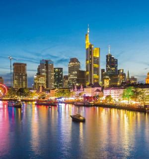 a city skyline at night with a river with boats