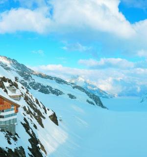 snieguotas kalnas su namu ant jo viršūnės