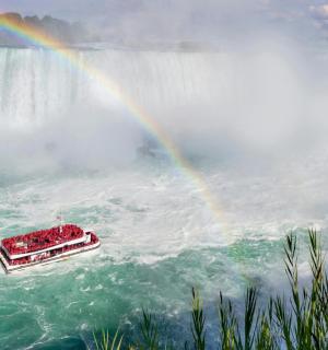 a rainbow over niagara falls with a boat