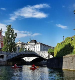 twee mensen in kano's in een rivier met een brug
