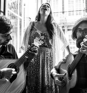 zwei Männer und eine Frau, die Gitarre spielen, und eine Frau, die steht