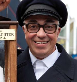 ein Mann mit Brille steht neben einem Schild