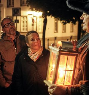 eine Gruppe von Männern steht um einen Mann herum, der eine Laterne hält