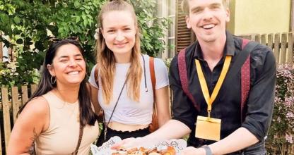 Ein Mann und zwei Frauen halten einen Teller mit Donuts.