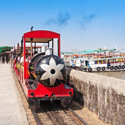 a red train parked next to a pier with boats