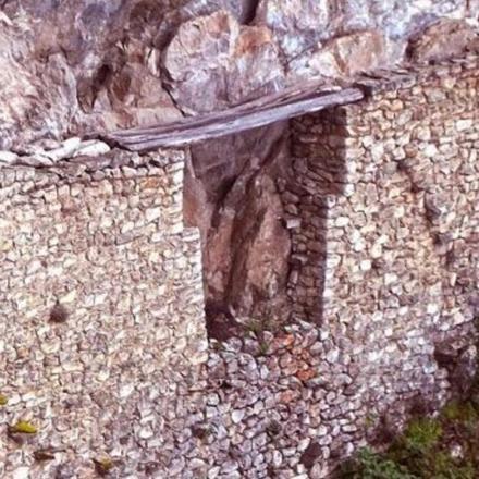 a stone wall with a wooden rail on it