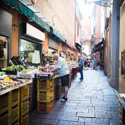 a man standing at a fruit and vegetable stand in a market