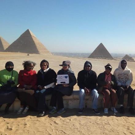 a group of people posing for a picture in front of pyramids
