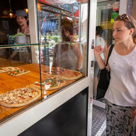 eine Frau steht vor einer Pizzeria