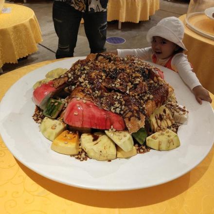 a little girl standing in front of a plate of food