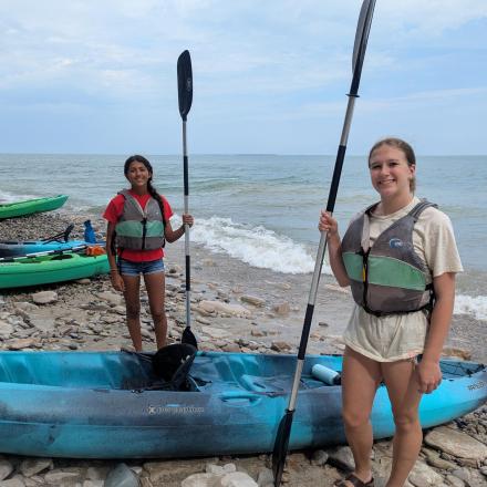 Zwei Frauen stehen neben einem blauen Kajak am Strand