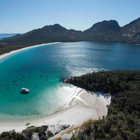 an aerial view of a beach with a boat in the water